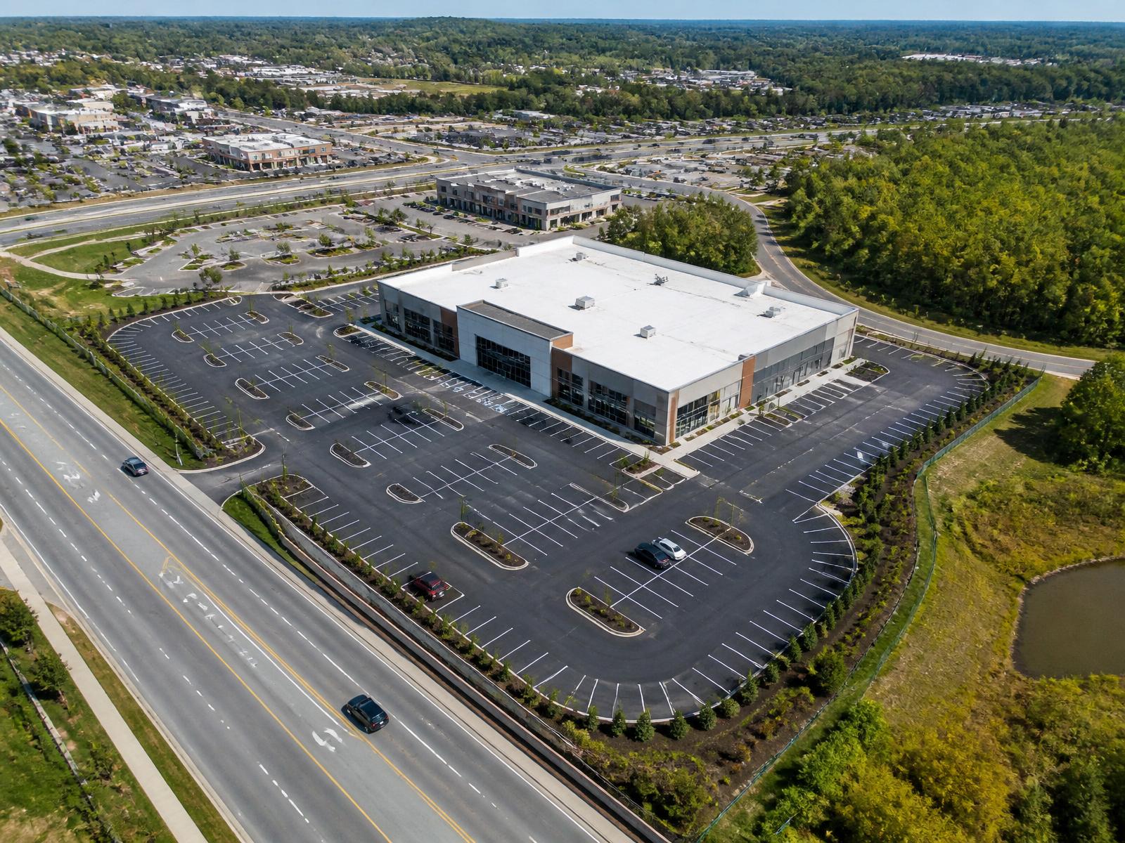 Aerial view of a modern commercial property with abundant parking and freeway access